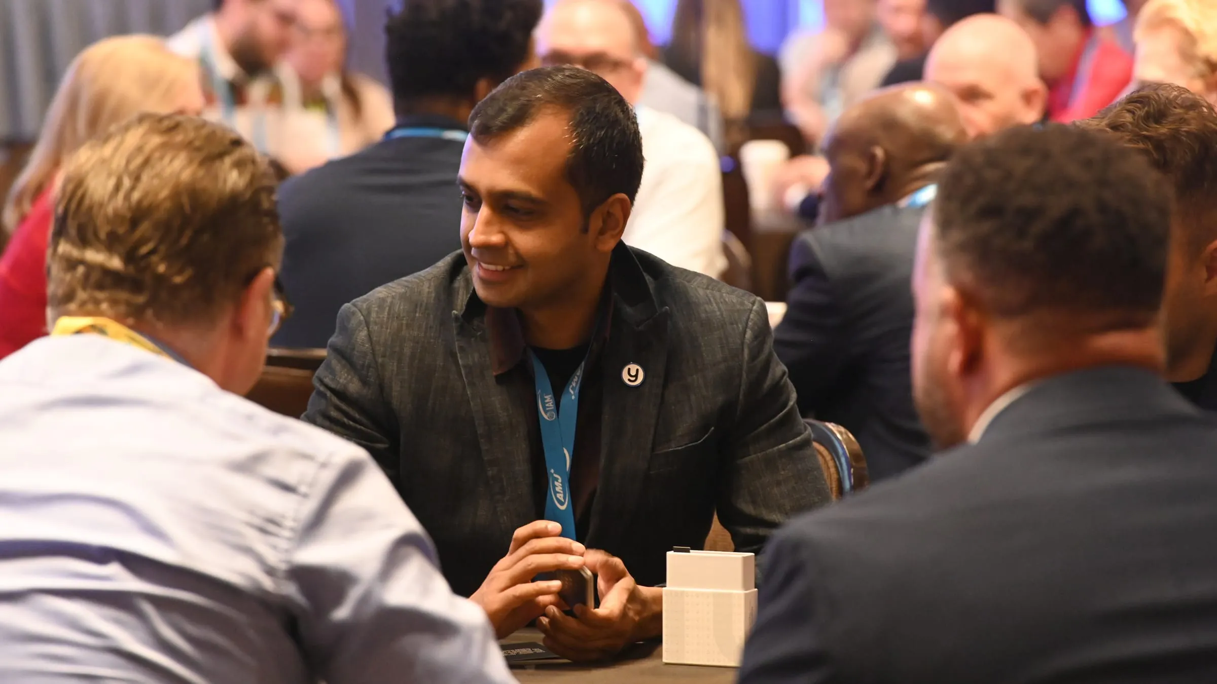 A member of the Yembo team in conversation across a table at the International Association of Movers annual meeting, wearing the Yembo pin.