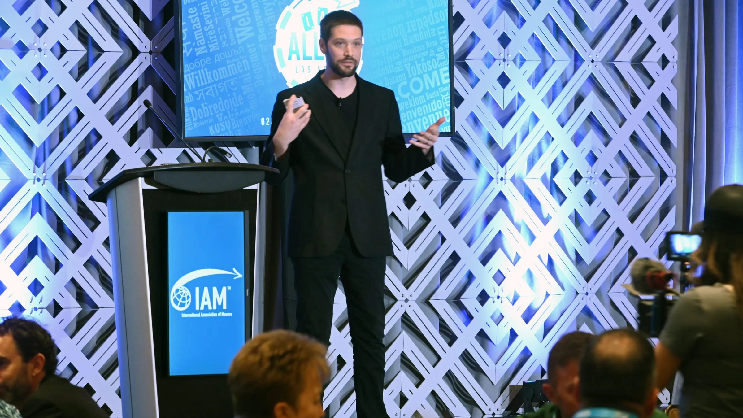 A member of the Yembo team presenting from the stage at the International Association of Movers annual meeting, in front of the conference welcome slide.