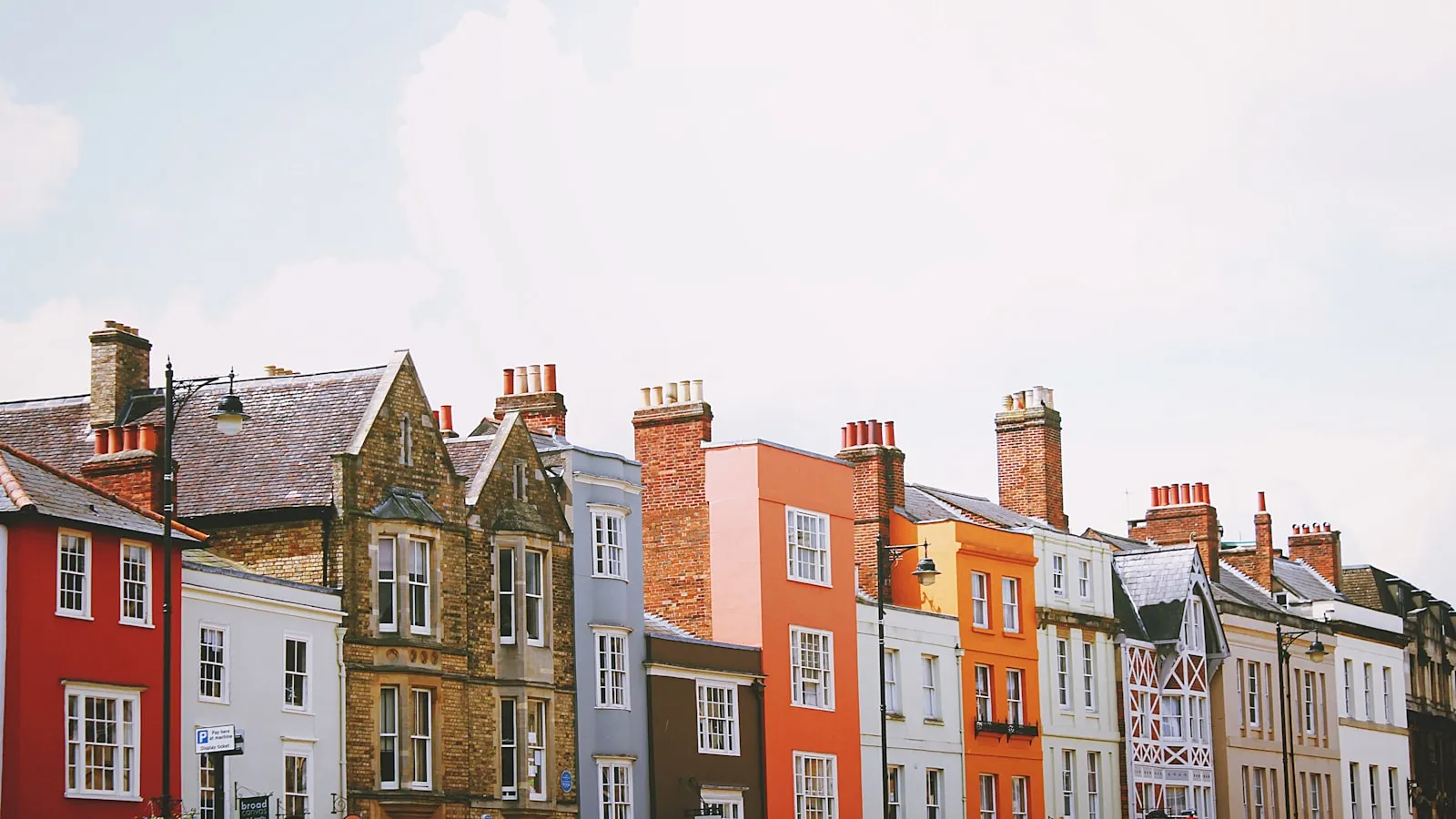 Assorted-color concrete houses under white clouds during daytime
