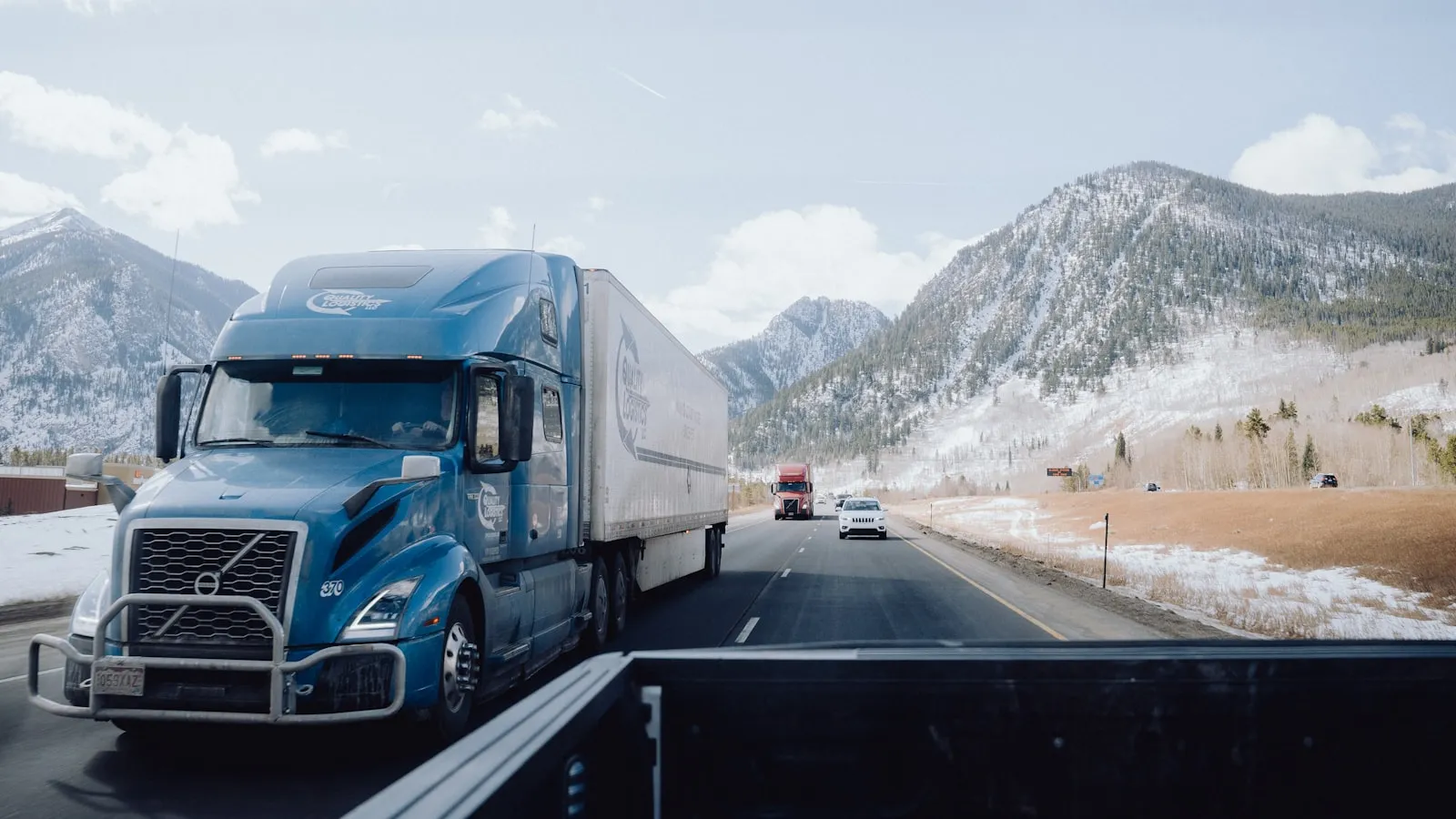 A blue semi truck driving down a mountain road