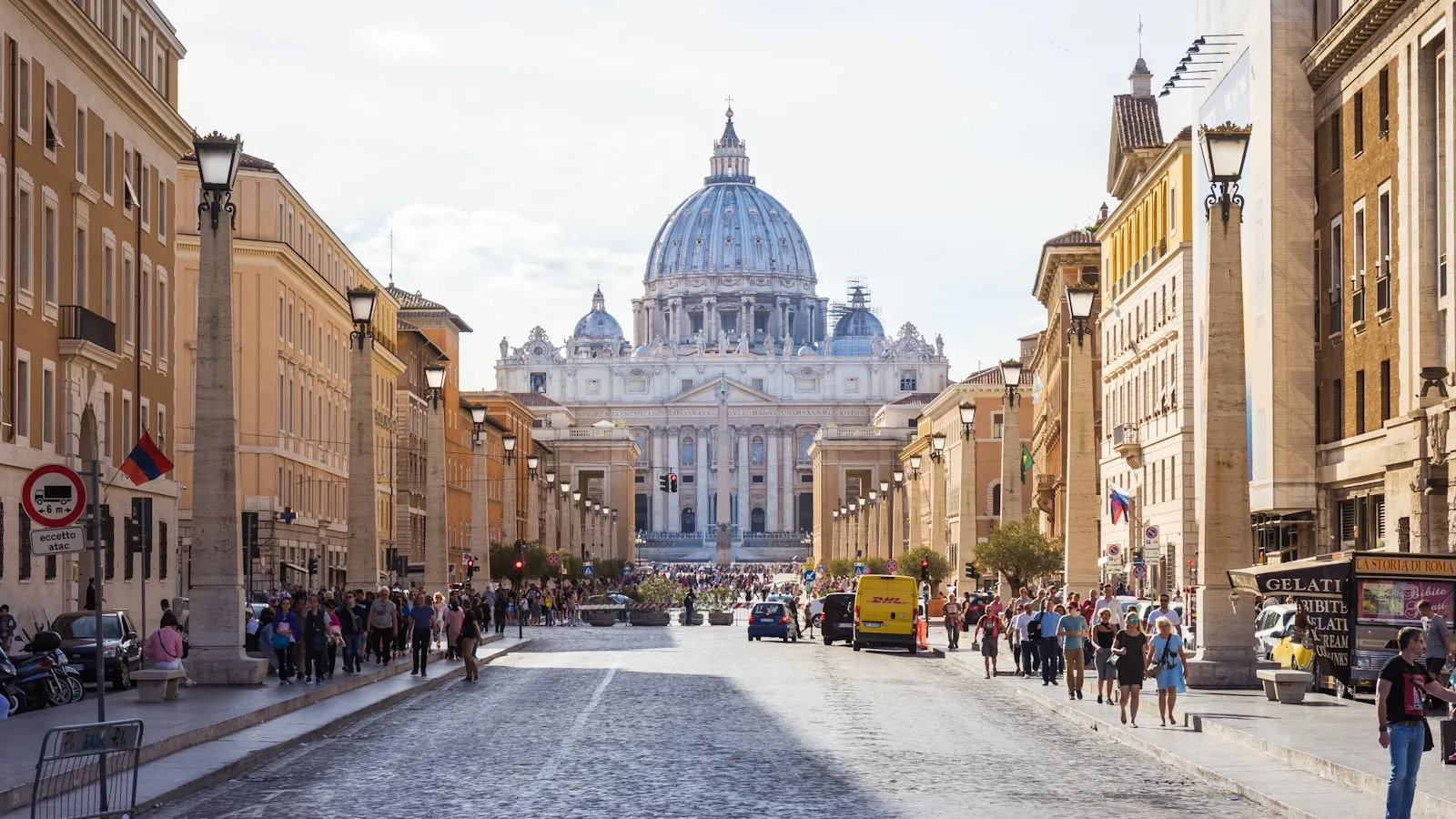 The dome of St. Peter's Basilica rising over a busy street in Rome.