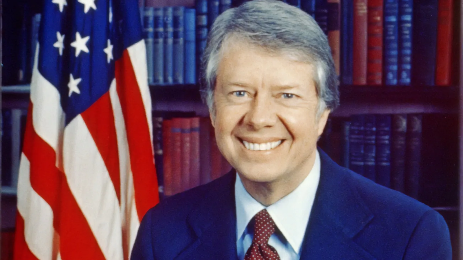 Official portrait of President Jimmy Carter in front of an American flag and shelves of books.