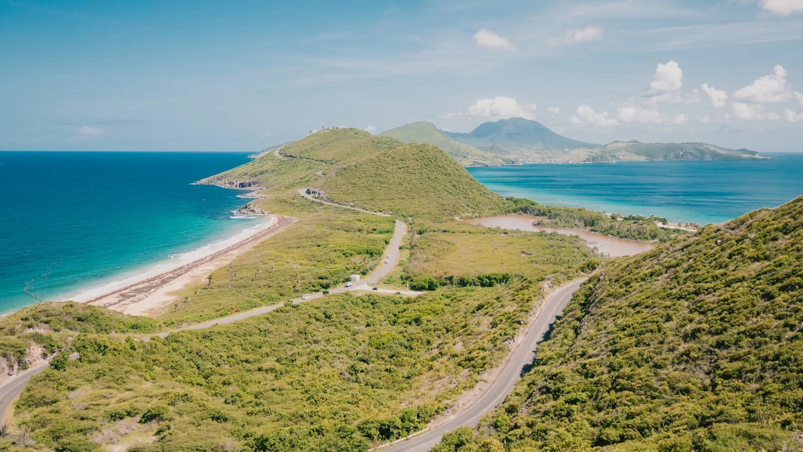 Coastal landscape with winding roads and distant mountains.