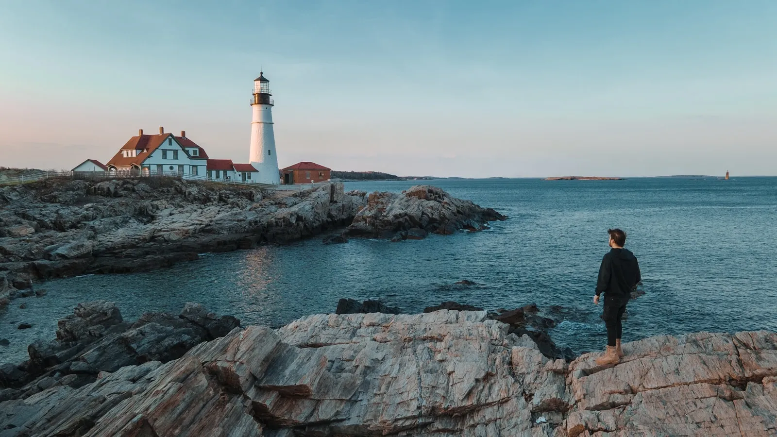 A man standing on a rock next to a lighthouse