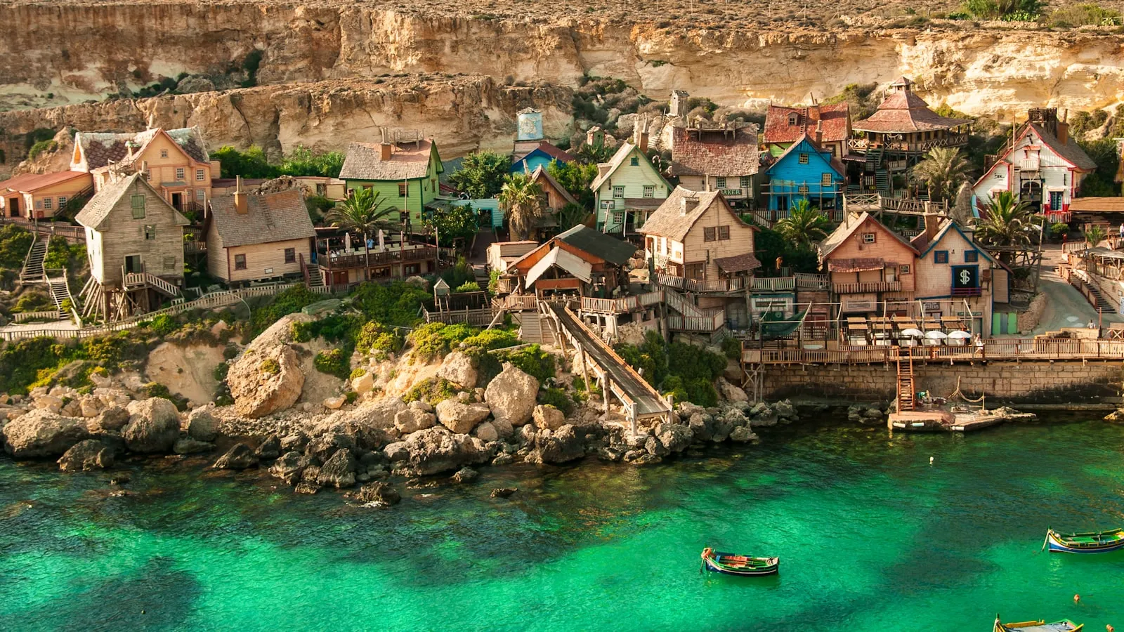 The colorful wooden houses of Popeye Village above a turquoise bay in Malta.