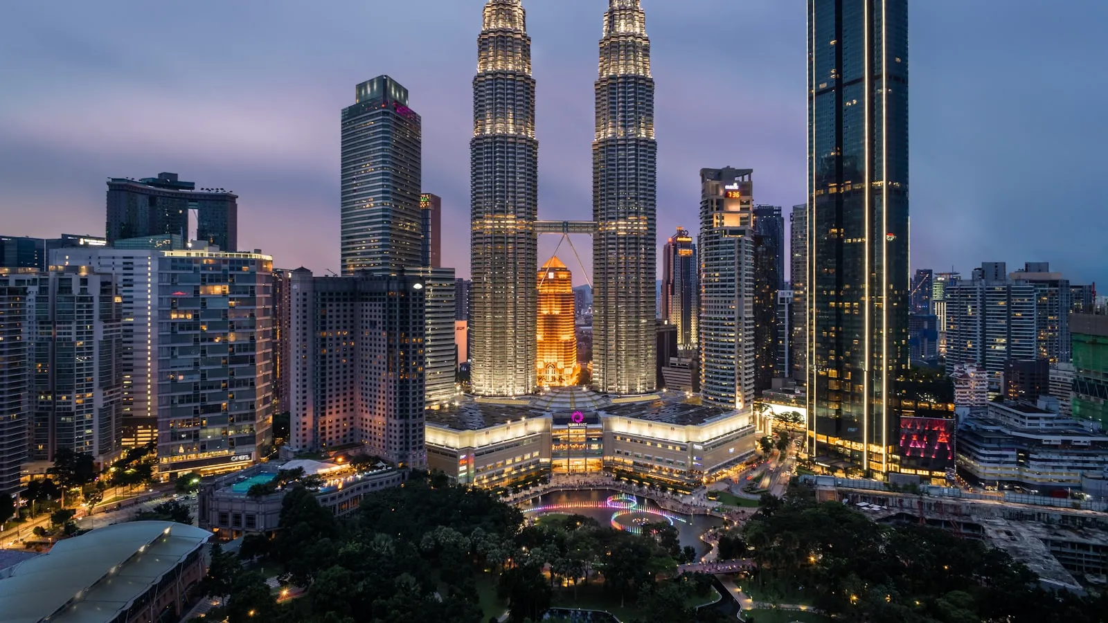 The Petronas Towers illuminated at night above a park in Kuala Lumpur, Malaysia.