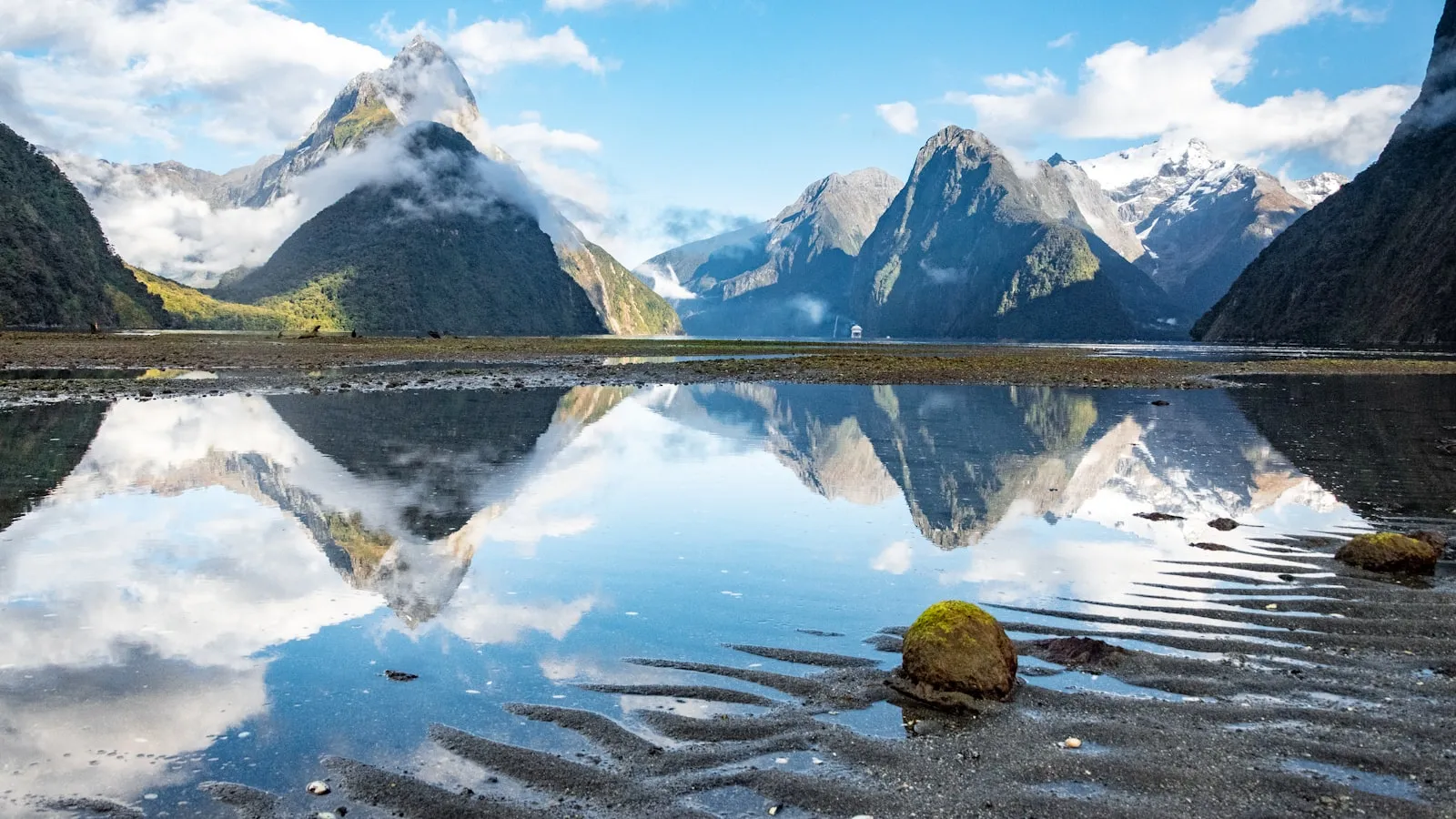 Body of water near mountain under blue sky during daytime