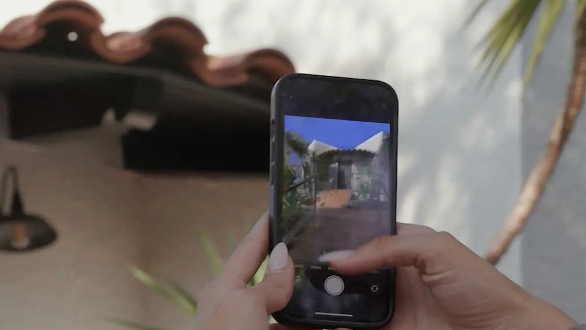 A policyholder photographing the exterior of their house with a phone.