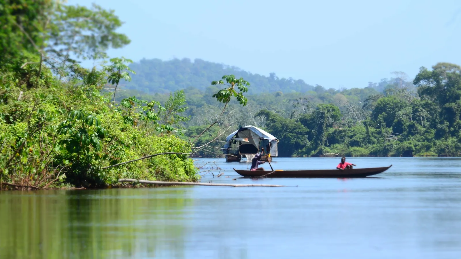 A small boat with two people on a wide river.