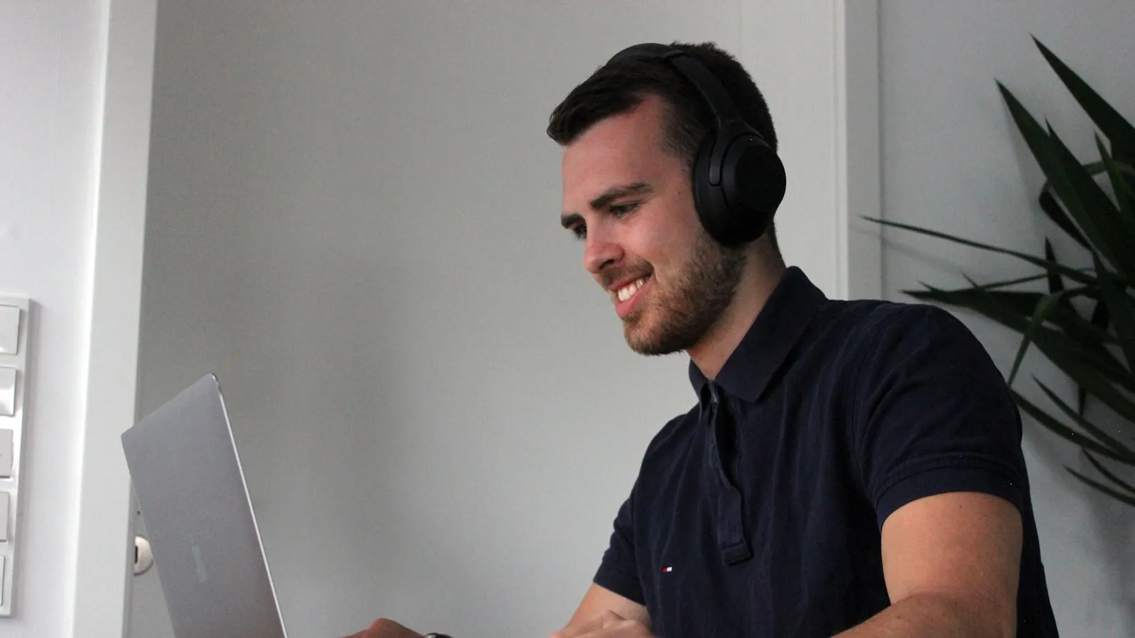 Man in black polo shirt using laptop computer