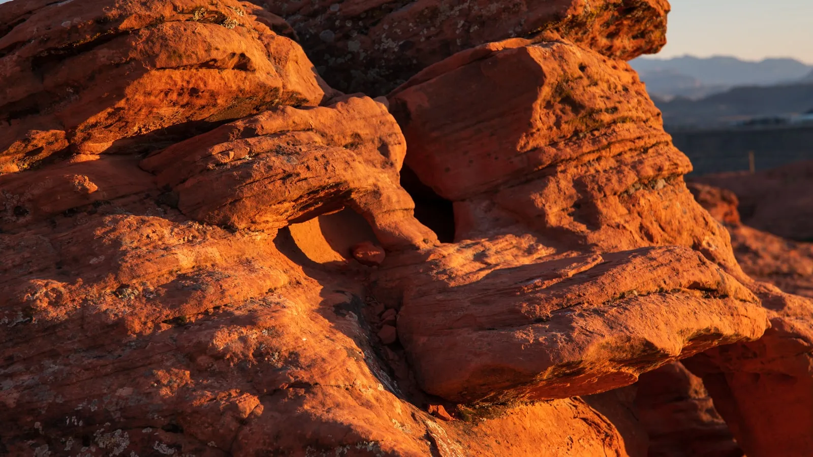 A rock formation in the desert with mountains in the background