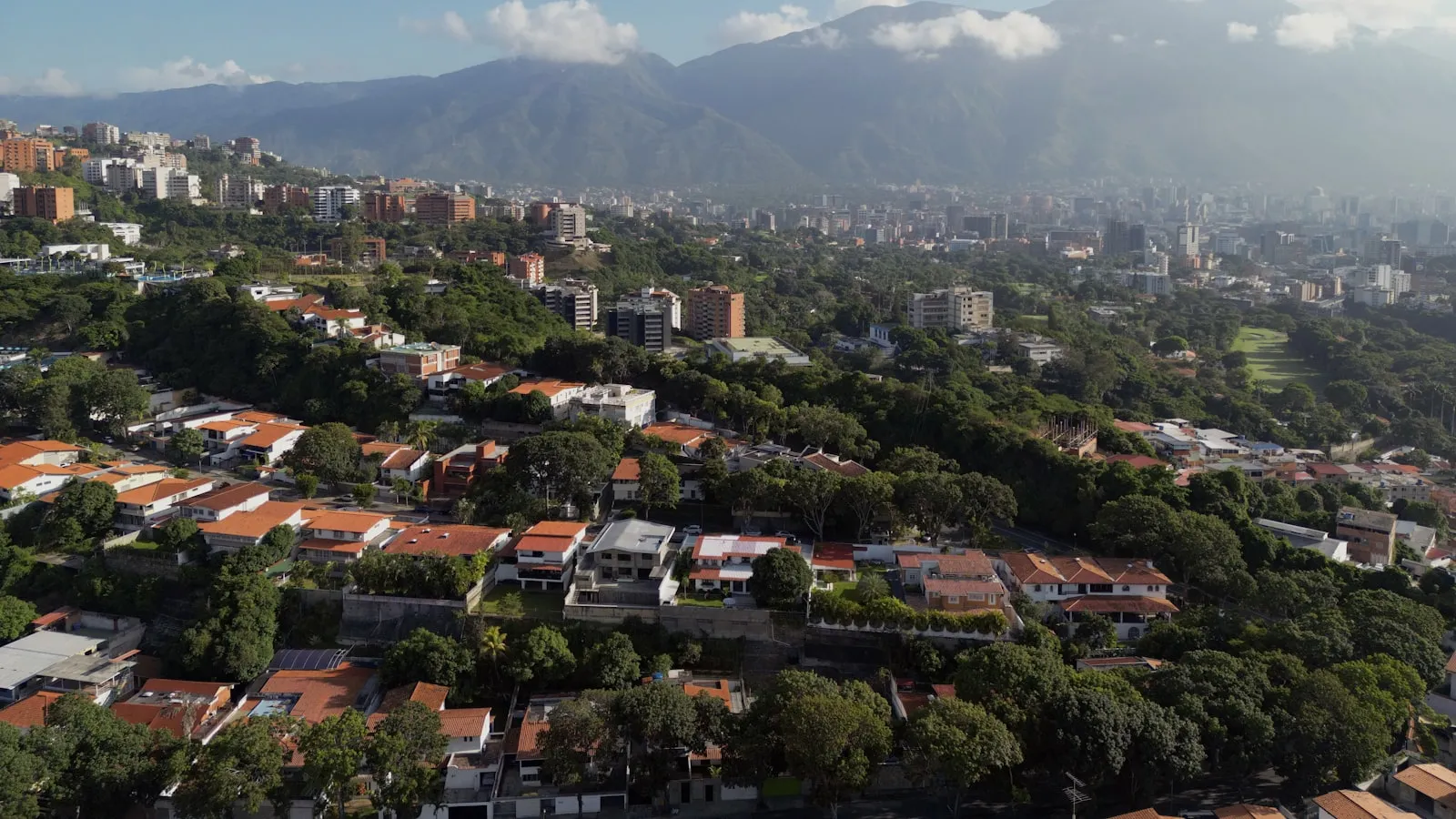 Aerial view of Caracas spreading toward the Avila mountains under morning clouds.