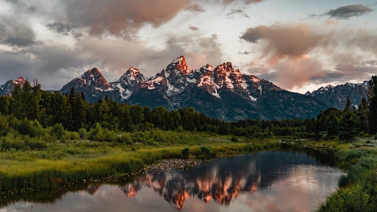 Green trees near lake and snow covered mountain during daytime